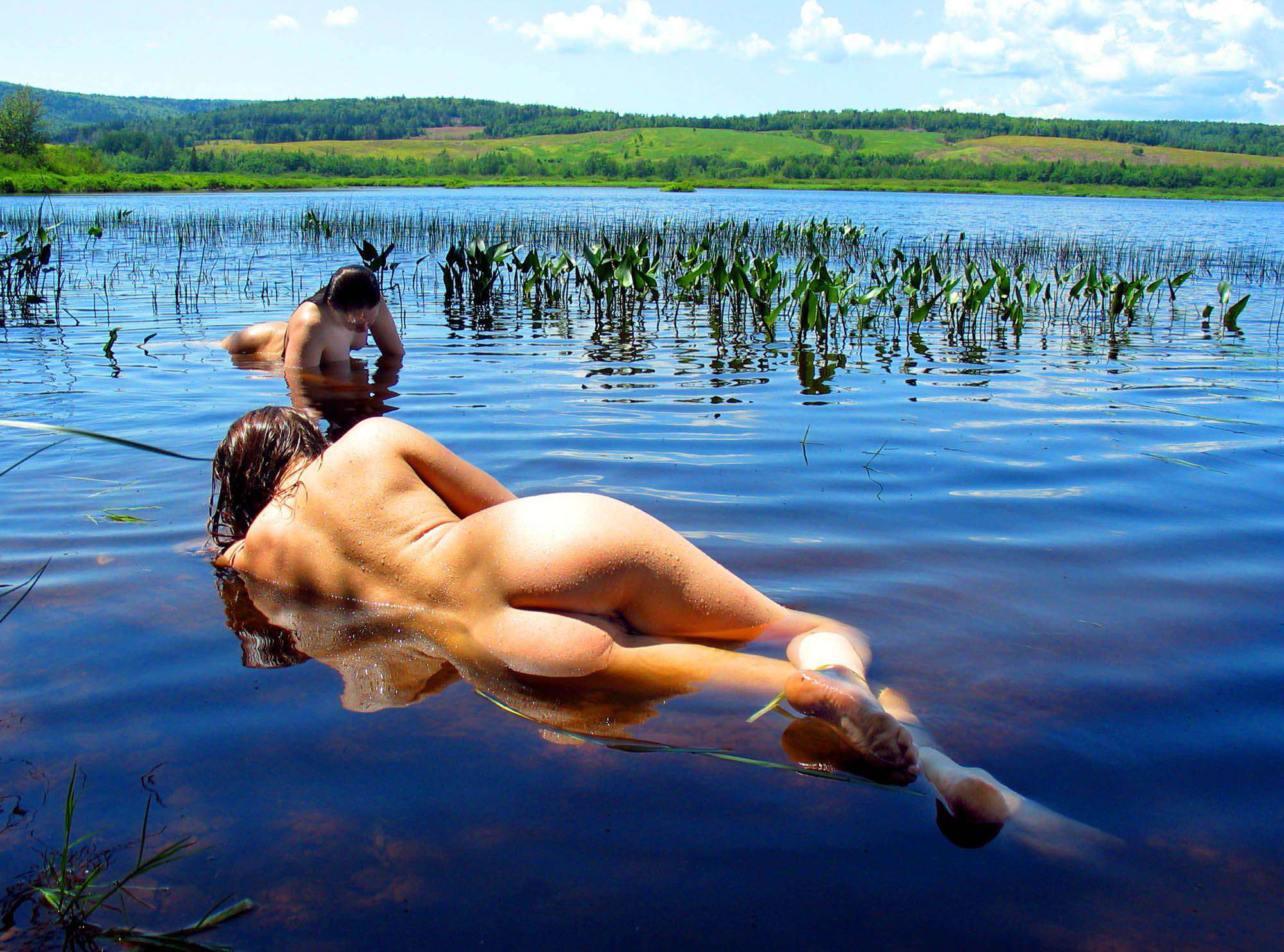 Красивая голая девушка купается в озере